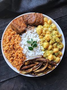 a white plate topped with rice, meat and beans next to other foods on a wooden table