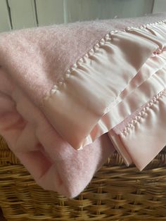 three pink pillows sitting on top of a wicker basket