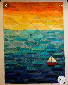 a quilted wall hanging with a sailboat in the ocean