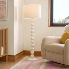 a living room with a chair, lamp and baby's crib in it