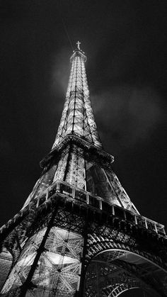 the eiffel tower lit up at night in black and white with its lights on