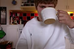 a young man is drinking from a coffee cup