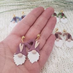 a hand is holding two small earrings on it