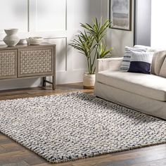 a living room with a couch, chair and rug on the hardwood floor next to a window