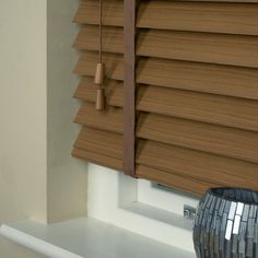 a close up of a window with blinds on the windowsill and a vase in front of it