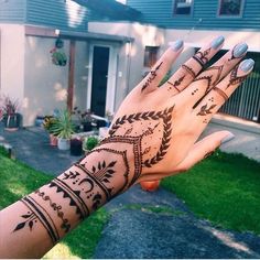 a woman's hand with hennap on it in front of a house