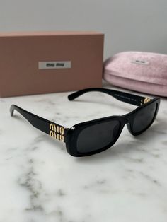 Brand new Miu Miu MU08ZS 1AB5S0 Sunglasses in Black.Featuring a black acetate frame with dark grey lenses.Gold Miu Miu detailing on temples.Size 53-20-140.100% authentic and unworn.Made in Italy.Box, case, cloth and paperwork included. Retail price $530. Sunglasses Luxury, Sunglasses Rectangular, Black Designer Sunglasses, Miu Miu Tinted Sunglasses For Evening, Miu Miu Sunglasses With Gradient Lenses For Evening, Miu Miu Gradient Lenses Sunglasses For Evening, Black Miu Miu Sunglasses With Mirrored Lenses, Elegant Black Miu Miu Sunglasses, Miu Miu Black Sunglasses With Mirrored Lenses