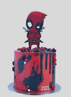 a red and black cake with a deadpool figure on top