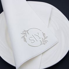 a white plate topped with two napkins and a monogrammed initial on it