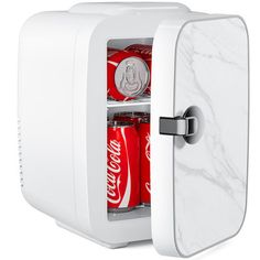 a white mini fridge with soda cans in it's door and marbled interior