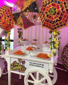 there are many colorful umbrellas hanging from the ceiling above a cart with food on it