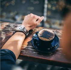 a person sitting at a wooden table with a cup of coffee in front of them