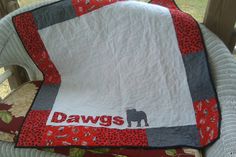 a chair with a quilt on it that says dawgs in red and grey