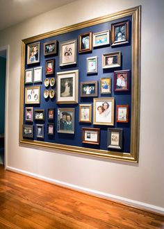 a large group of framed pictures on a wall in a room with hard wood flooring