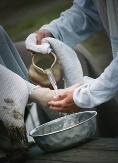 someone is washing their hands with water from a pitcher