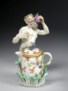 a figurine is sitting on top of a teapot and holding a flower