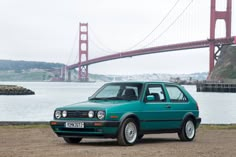 a green car parked in front of the golden gate bridge