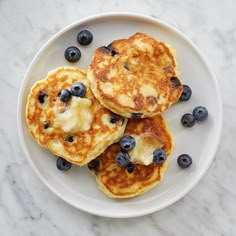 three pancakes with blueberries on a white plate