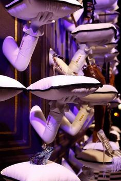 white shoes are hanging from the ceiling in front of purple lights and pillows on display