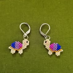 the earrings are made out of beads and have an image of a bird on it