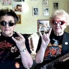 two women sitting on a couch with their fingers up in the air and one holding a guitar