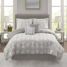 a bed with white and grey comforters in a room