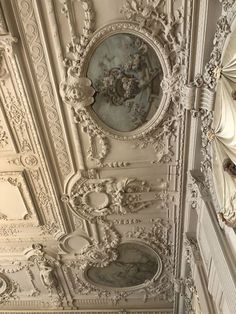 an ornate ceiling in the middle of a room with white walls and carvings on it