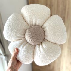 a person holding up a white flower cushion