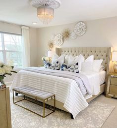 a large white bed sitting in a bedroom next to a window