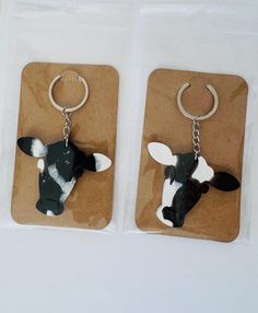 two cow key chains are on display in plastic bags, one is black and the other is white