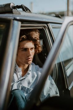 a man sitting in the driver's seat of a car with his head out the window