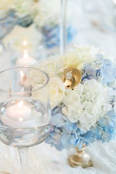 there is a vase with flowers and candles on the table in front of two wine glasses