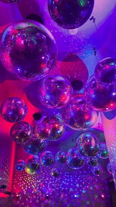 many shiny disco balls are hanging from the ceiling in this room with purple and blue lighting