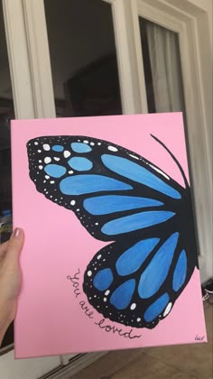 a hand holding up a pink and blue butterfly