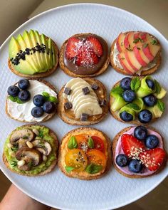 a white plate topped with sandwiches covered in fruit and veggies on top of each other