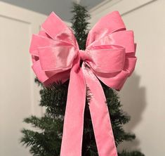 a pink bow on top of a christmas tree