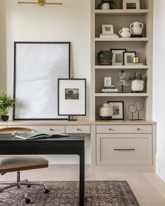 a home office with white bookcases and black desk