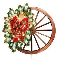 a christmas wreath on top of a wooden wheel with lights and bows hanging from it