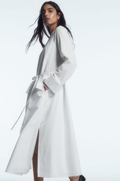 This season, the COS womenswear team reimagine the perennial shirt dress. Crafted from lightweight cotton poplin, it's cut to hit at the ankle and designed with a collarless neckline and an overlapping storm flap detail at the back that borrows from classic trench coats. It's detailed with an elasticated gathered back panel and tonal belt that allows you to personalise the shape. Relaxed fitButton closureSide slits Shell: 100% Cotton (excluding trims) / Machine wash Back length of size EU 36 is 122.3cm / Model wears a size EU 36 Chic Cotton Maxi Shirt Dress, Cotton Maxi Length Shirt Dress For Daywear, Cotton Maxi Shirt Dress For Daywear, Chic Long Cotton Shirt Dress, Spring Cotton Dresses With Belted Cuffs, Chic Long Shirt Dress For Daywear, Cotton Dresses With Belted Cuffs, Relaxed Fit Maxi Shirt Dress For Daywear, Elegant Poplin Summer Dress