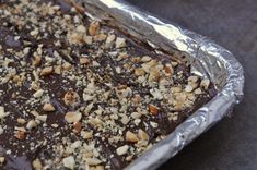 a pan filled with chocolate and nuts sitting on top of a metal foil covered table