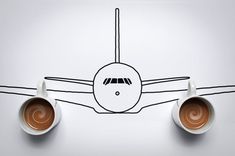 two coffee cups with saucers in front of a drawing of an airplane on the wall