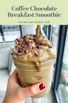 a person holding up a drink in front of a window with the words coffee chocolate breakfast smoothie