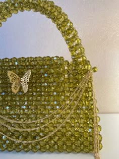 a handbag made out of green beads with a butterfly on the clasp and chain