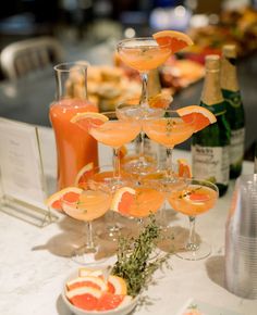 a table topped with lots of glasses filled with drinks and garnished with orange slices