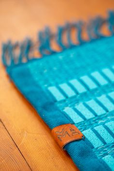 a close up of a blue cloth on a wooden floor with a leather patch in the middle