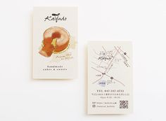 two business cards sitting next to each other on top of a white surface with a drawing of a donut