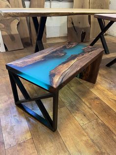 a wooden table sitting on top of a hard wood floor covered in blue paint and black metal