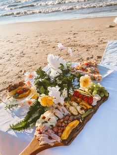 a platter on the beach with food and flowers in it is ready to be served