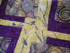 a purple and yellow quilt with birds sitting on it's center piece in the middle