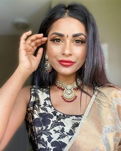 a woman with dark hair wearing a necklace and matching earrings is posing for the camera